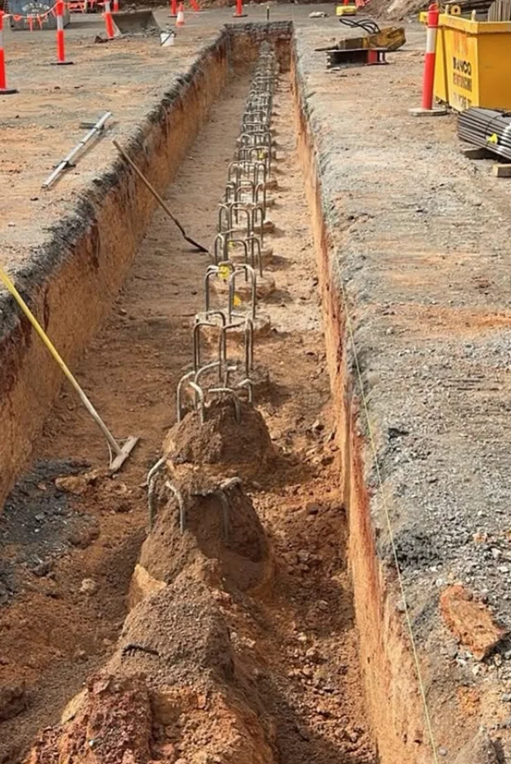 Deep beam trench with a steel reinforcement cage set in place, trench walls cut clean and benched